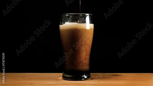 A pint of dark ale beer or stout is poured up. photo