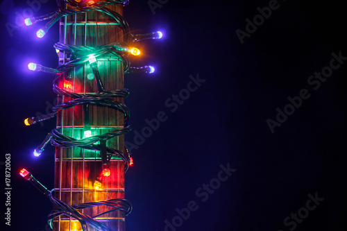 Merry christmas guitar wrapped by colorful garland as a gift background