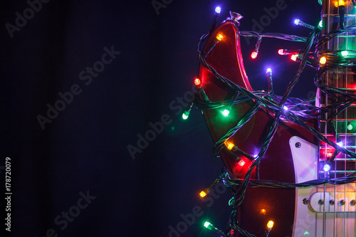 Merry christmas guitar wrapped by colorful garland as a gift background