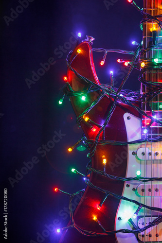 Merry christmas guitar wrapped by colorful garland as a gift background