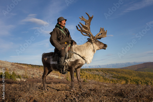 Old Mongolian man riding a reindeer. photo