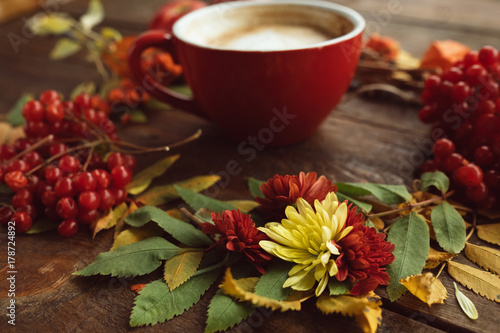 Cup of hot latte on the autumn background. Fall bouquet on the wooden rough surface. © golubovy