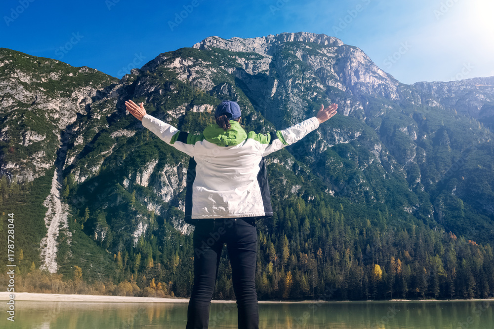 Naklejka premium Frau steht mit ausgestreckten Armen vor großen majestätischen Bergen Panorama Rückansicht