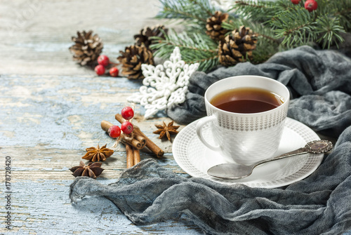 Cup of tea with spices and Christmas decoration on wooden blackboard