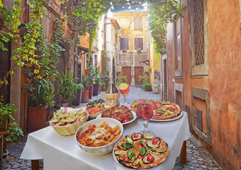 A summer  dinner .Pasta , pizza  and homemade food arrangement  in a restaurant  Rome   .Tasty and authentic Italian food.