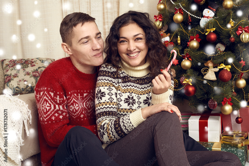 Happy couple celebrates Christmas at home. New year eve, ornated fir tree. Winter holiday and love concept. Happy couple celebrates Christmas at home. New year eve, ornated fir tree. Winter holiday and love concept.