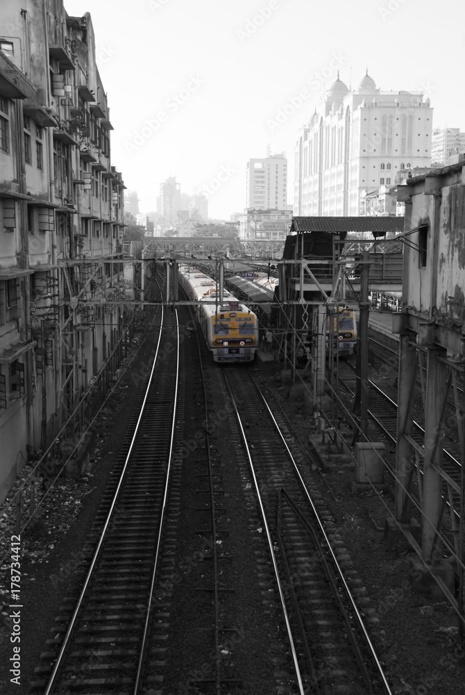 Naklejka premium Suburban Railway. The train approaches the station against the background of tall buildings