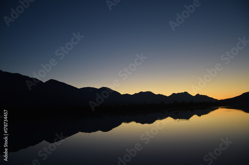 Quadro em tela Last glimpse of a sunset with mountain silhouette in the water
