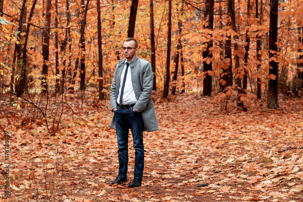 Modern handsome attractive man in gray coat in autumn forest. Fashion and clothing concept. Free place for text. Modern handsome attractive man in gray coat in autumn forest. Fashion and clothing concept. Free place for text.
