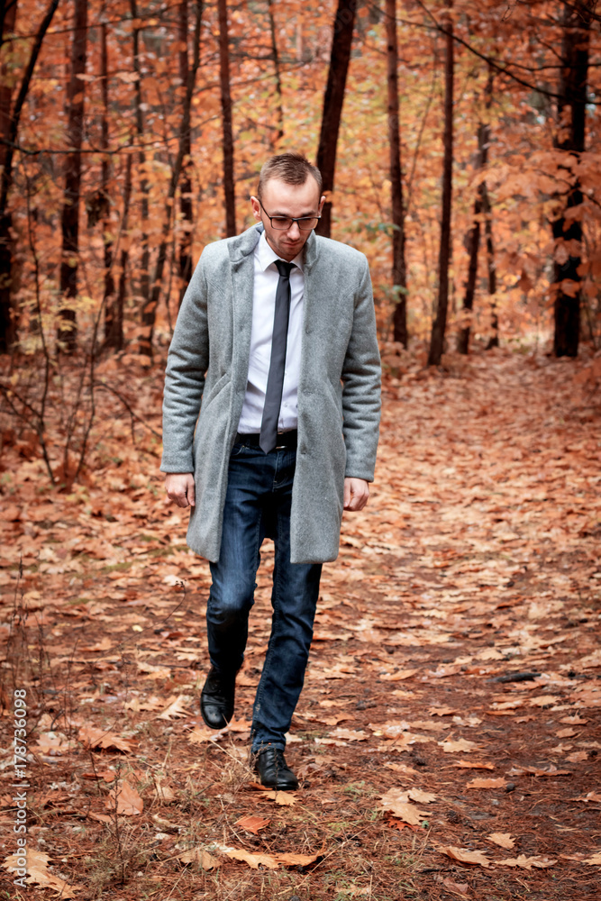 Modern handsome attractive man in gray coat in autumn forest. Fashion and clothing concept. Modern handsome attractive man in gray coat in autumn forest. Fashion and clothing concept.