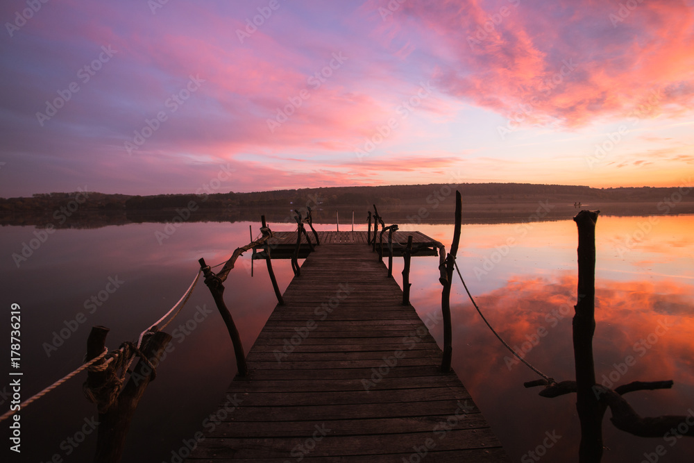 Obraz premium Perspective view of a wooden pier on a river at sunset