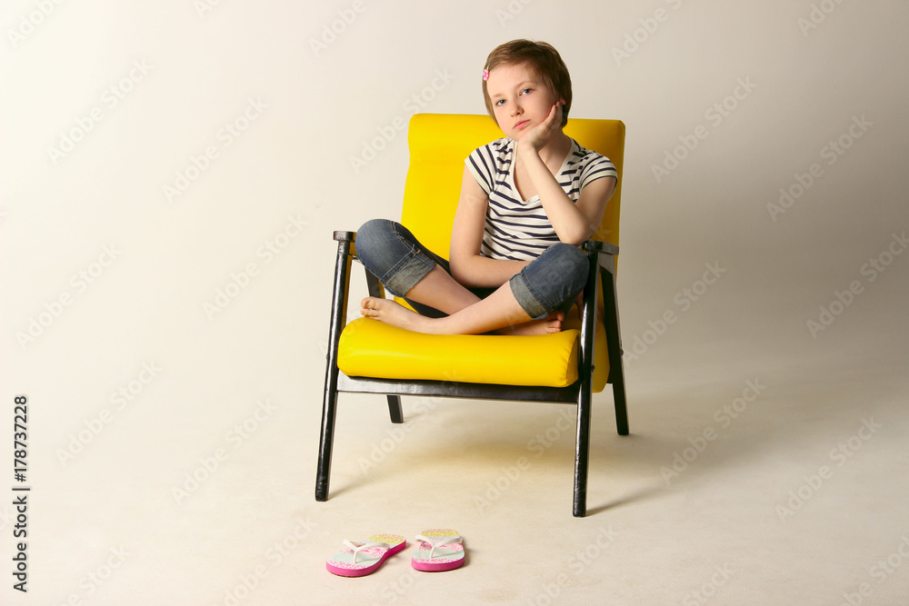 Dreaming young girl sitting on yellow chair. Shot of a little girl relaxing on a chair at home. Dreaming young girl sitting on yellow chair. Shot of a little girl relaxing on a chair at home.