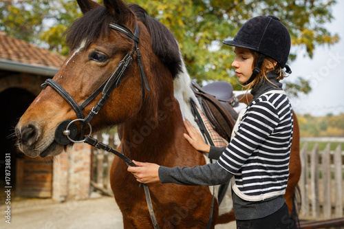  Preparing for training. Teenage girl with her horse in front of a stable © cherryandbees