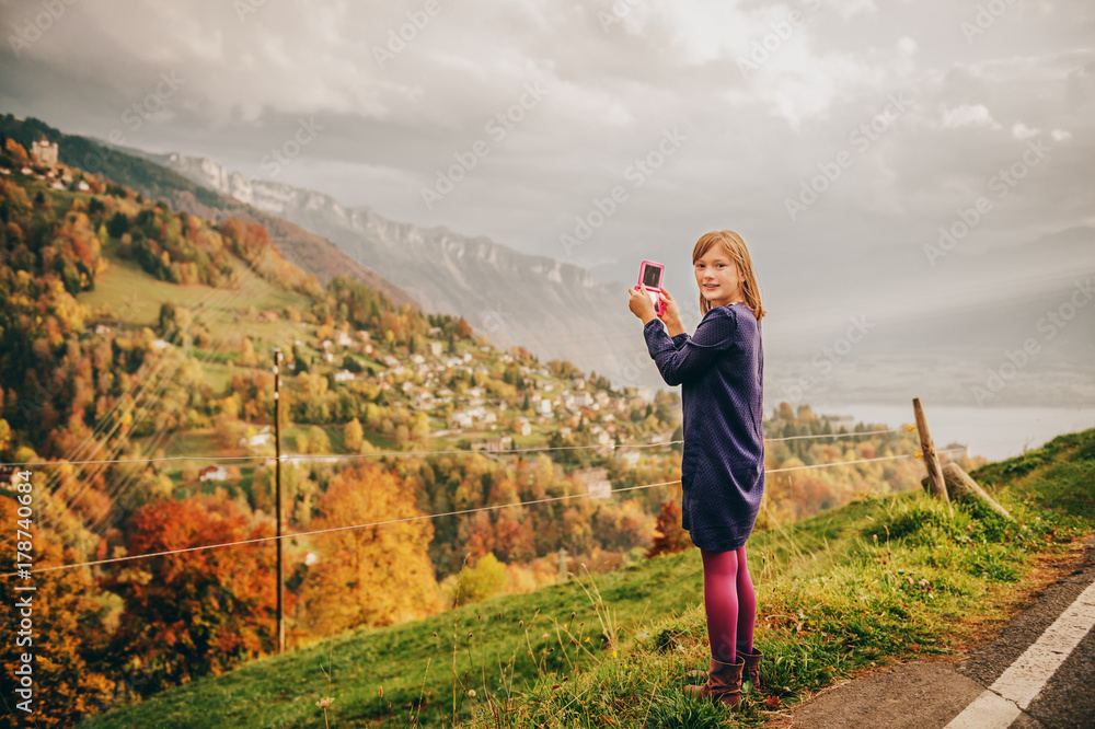 Cute little girl taking pictures of amazing mountain landscape, travel with children. Image taken in canton of Vaud, Switzerland