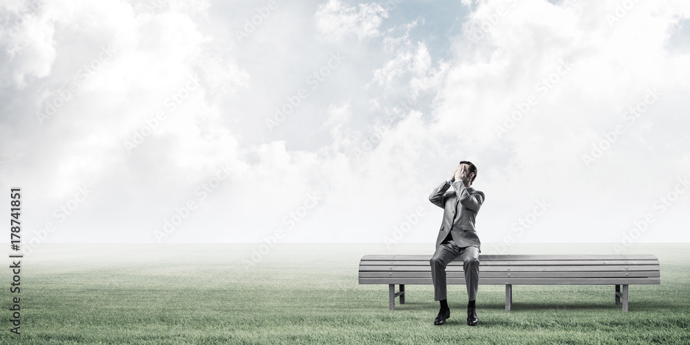 Young man in summer park on bench do not want to see anything