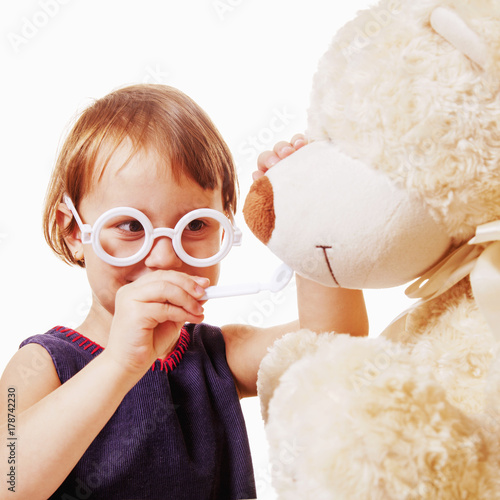 Cute little child girl playing dentist with teddy bear (Children's dentistry, health, medicine concept)