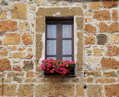 italian window with nice flowers in old stone house, Tuscany, Italy.