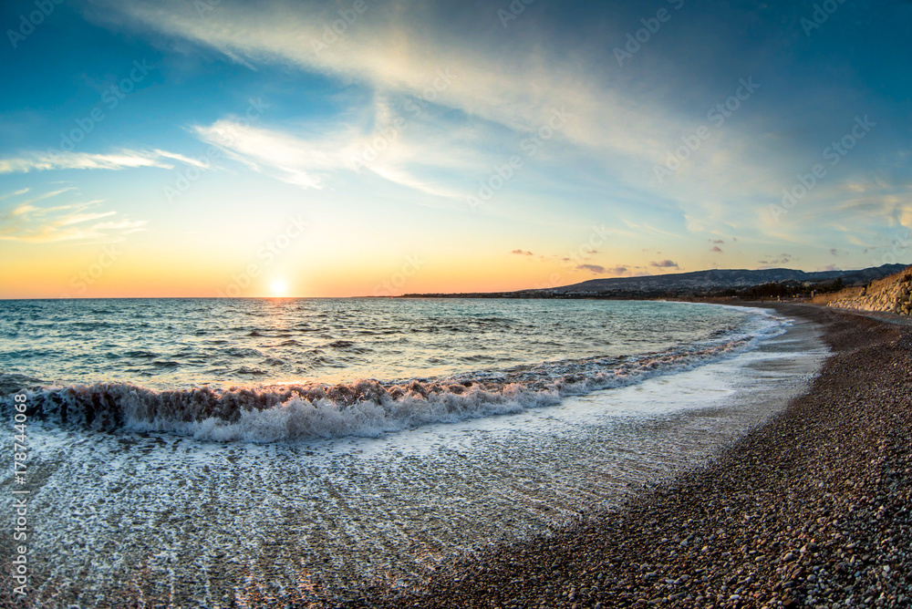 View of the beautiful sunset over the sea with wild pebble beach coast. Fisheye effect