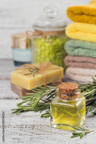 Natural cosmetic oil and natural handmade soap with rosemary on rustic wooden background.