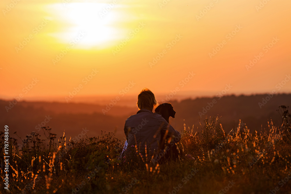 Frau umarmt ihren Hund im romantischen Sonnenuntergang