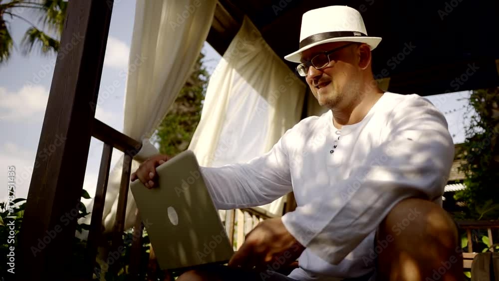The adult man closes the lid of the laptop and puts a hat on it, the person has finished work and starts to rest The adult man closes the lid of the laptop and puts a hat on it, the person has finished work and starts to rest