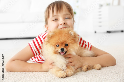 Cute girl with little dog on floor at home