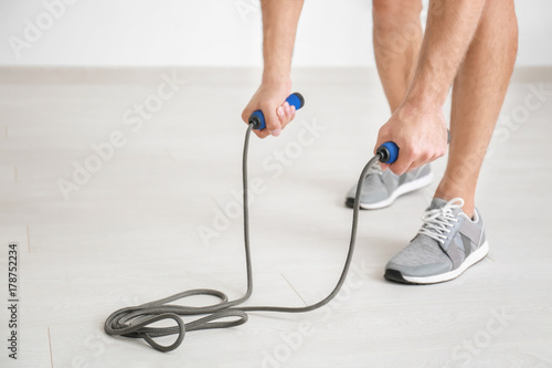 Young man with jumping rope indoors