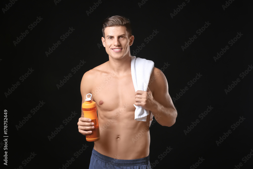 Young man holding bottle with protein shake on black background Young man holding bottle with protein shake on black background
