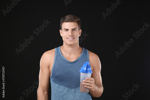 Young man holding bottle wi...