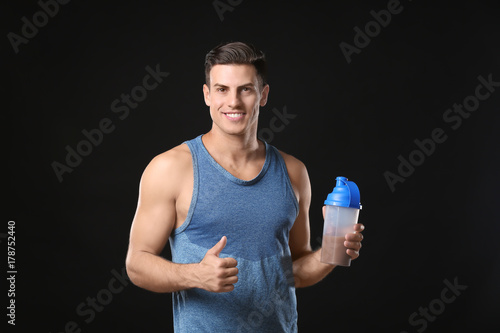 Young man holding bottle wi...