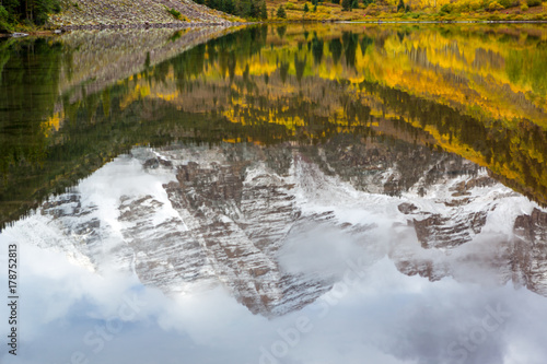 Reflection of Maroon Peak on Maroon Lake and aspen trees with its gold yellow leaves in fall foliage autumn season in a bright day light sunny day cloudy blue sky, Aspen, Colorado, USA. photo