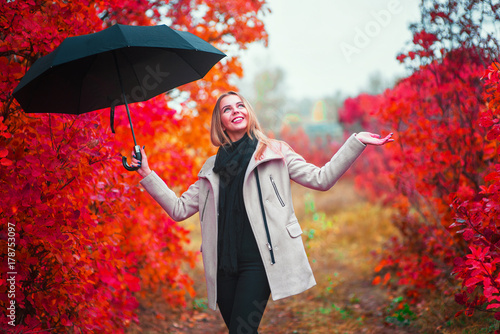 Happy woman with umbrella checking for rain. Woman wearing in gray coat in autumn photo