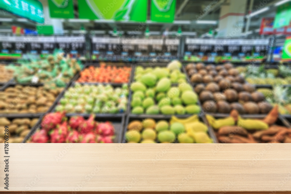 Empty wooden table and supermarket blurred fruits background Empty wooden table and supermarket blurred fruits background