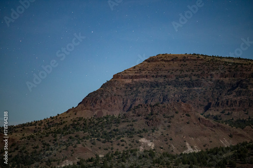 Desert mountain cliff at night with blue moonlit sky