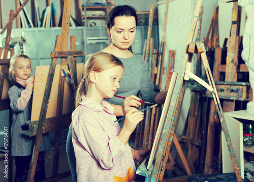 Woman teacher assisting girl during painting class