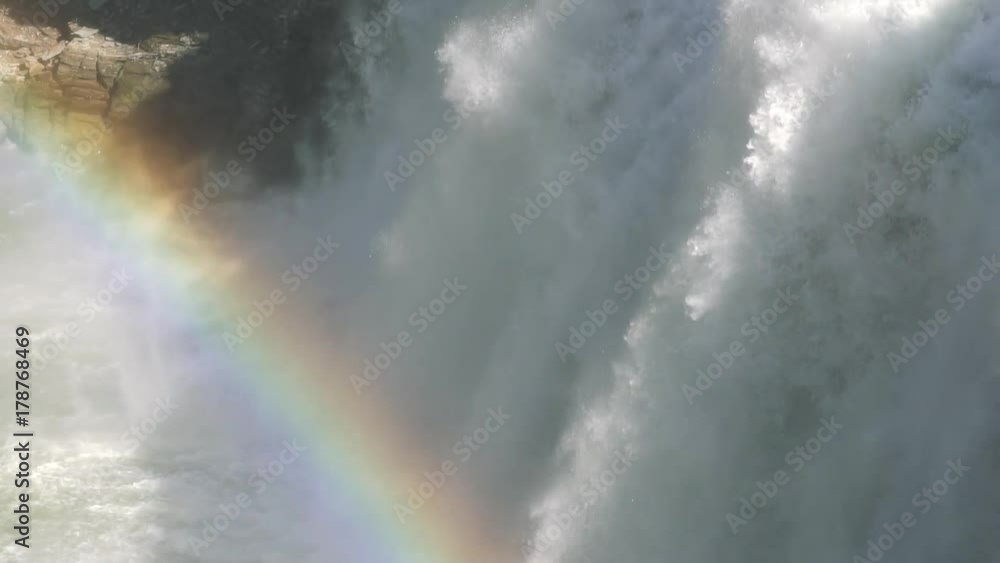 Rainbow forms in the sunlit spray of the middle falls waterfall in Letchworth park in spring Rainbow forms in the sunlit spray of the middle falls waterfall in Letchworth park in spring
