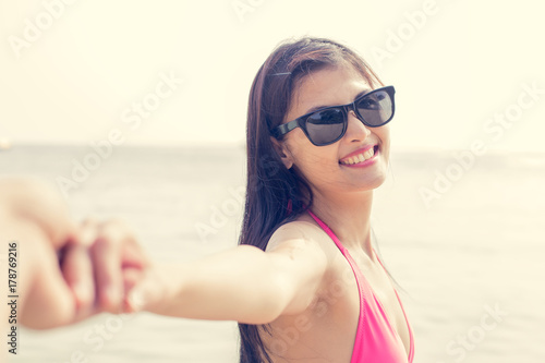 Portrait of Young girl holding hand on the beach with attractive smiling on the sea background. Vintage tone.