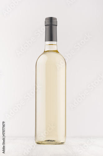 Transparent wine bottle with white wine on white wooden board, mock up, vertical. Template for advertising, design, branding identity.