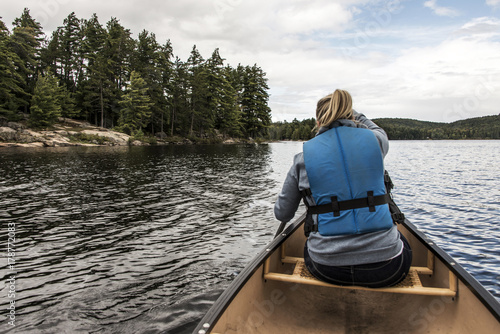 Girl canoeing with Canoe on the lake of two rivers in the algonquin national park in Ontario Canada on sunny cloudy day