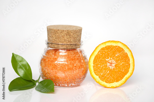 bath salt with  extract of orange. Orange sea salt in a glass jar and orange in a cut on a light background. Organic Citrus Natural Cosmetics