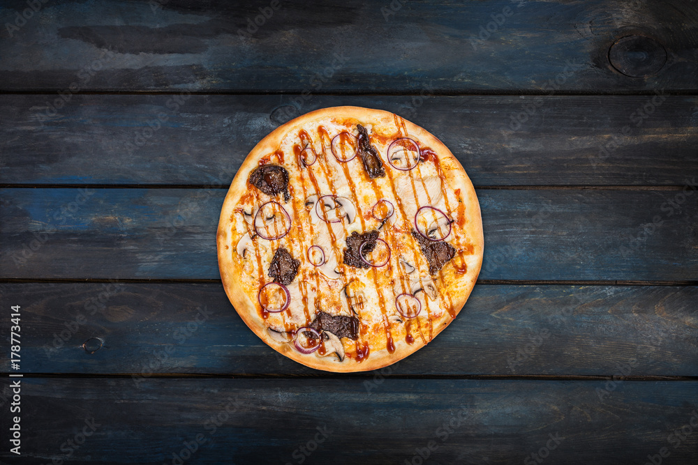 Delicious pizza with mushrooms chicken meat and onions on a dark wooden background. Top view center orientation Delicious pizza with mushrooms chicken meat and onions on a dark wooden background. Top view center orientation