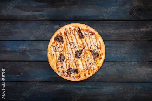 Delicious pizza with mushrooms chicken meat and onions on a dark wooden background. Top view center orientation