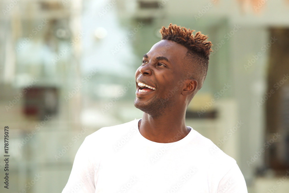Close up young black man looking away and laughing Close up young black man looking away and laughing