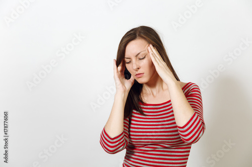 Pretty European worried and pensive brown-haired woman with healthy clean skin and headache, dressed in red and grey clothes lost in thought and conjectures, on a white background. Emotions concept.