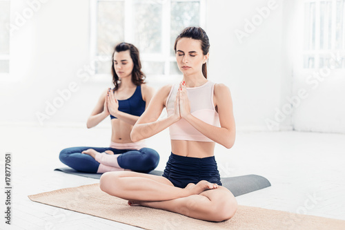 Studio shot of a young women doing yoga exercises on white background