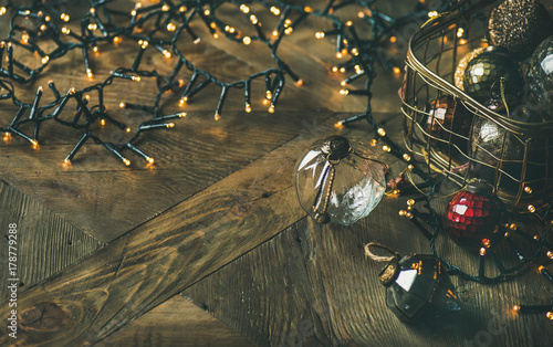 Christmas or New Year background, preparing for holiday. Christmas tree toy decoration glass balls in vintage box and light garland over rustic wooden background, copy space