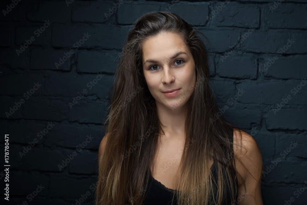 Young woman leaning against black brick wall Young woman leaning against black brick wall