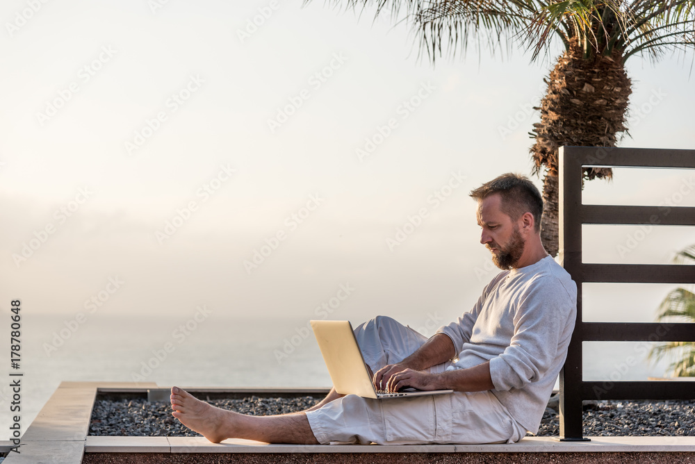 Young man with laptop at sunset