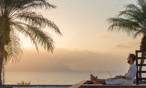 Young man with laptop at sunset