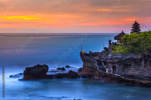 The Pilgrimage Temple of Pura Tanah Lot at sunset, island with an Indonesian shrine on the ocean, long exposure, copy space for text. Tanah Lot Temple, Beraban, Bali, Indonesia. photo